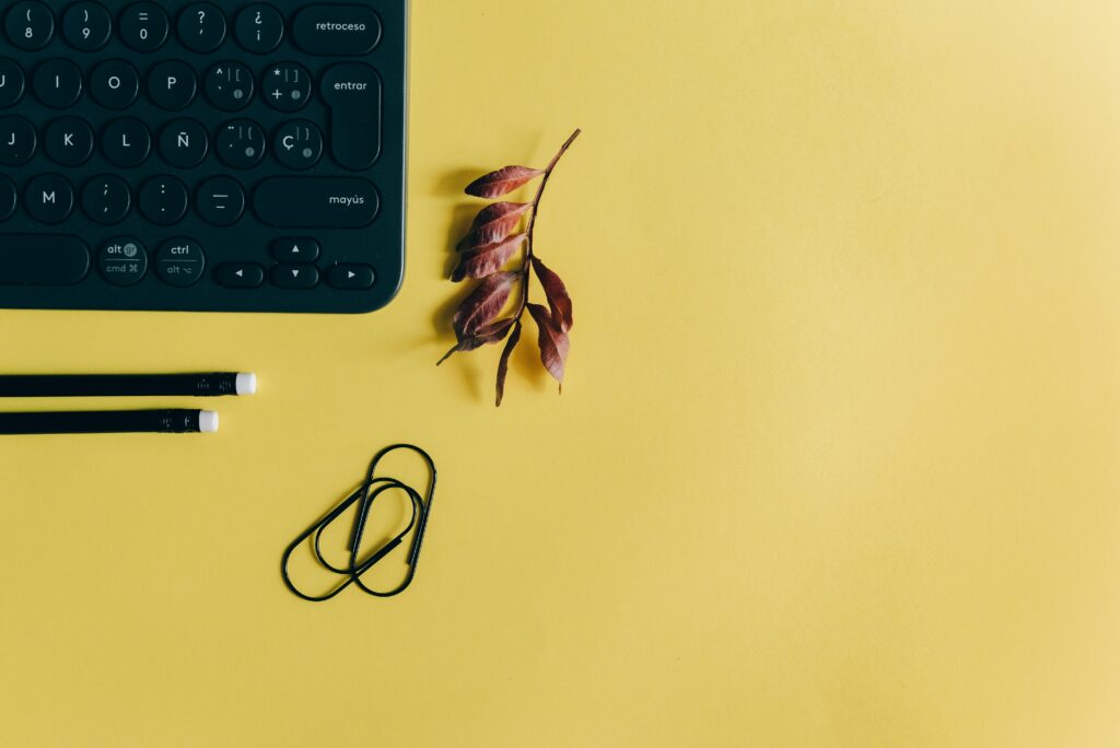 pexels photo 5417684 5417684 A minimalist workspace featuring a keyboard, pencils, and paperclips on a yellow background.